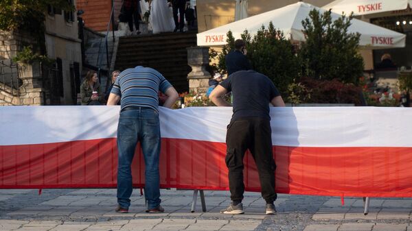 Польский флаг крепят перед митингом партии Право и справедливость в Сандомире, Польша