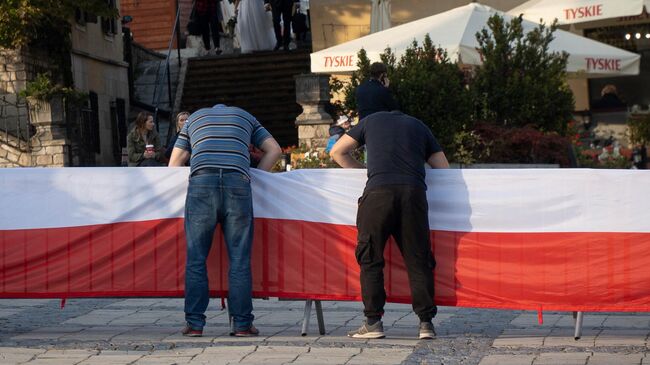 Польский флаг крепят перед митингом партии Право и справедливость в Сандомире, Польша