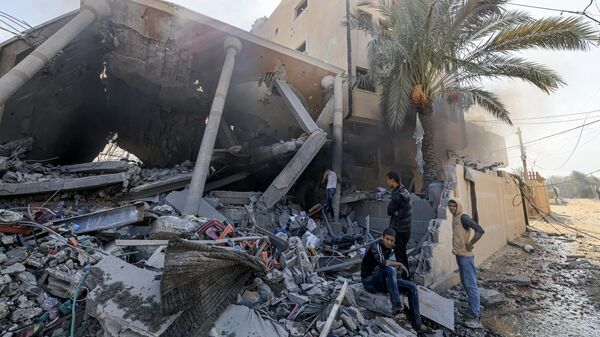 Палестинцы возле рухнувшего после израильского удара здания в Хан-Юнисе на юге сектора Газа