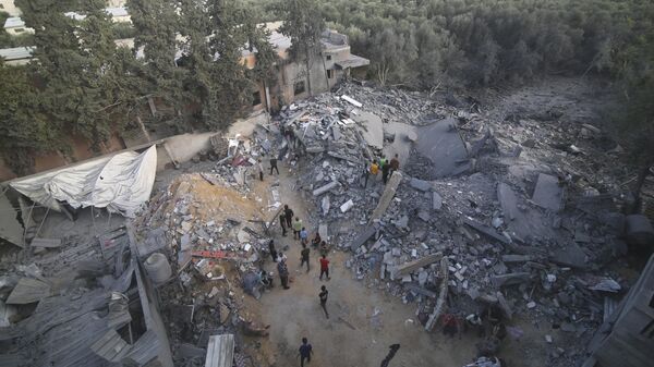 Палестинцы стоят у здания, разрушенного в результате израильского авиаудара, сектор Газа. Архивное фото