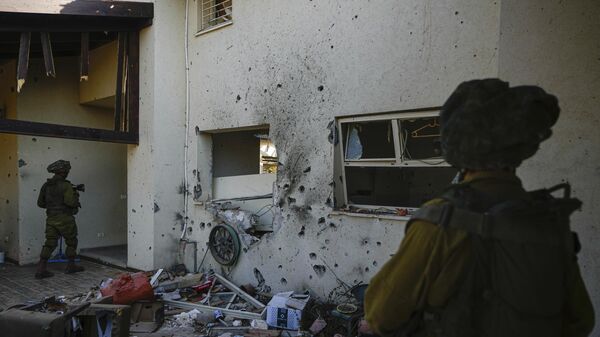 Израильские солдаты рядом с домом, поврежденным боевиками Хамаса, в кибуце Беэри в Израиле