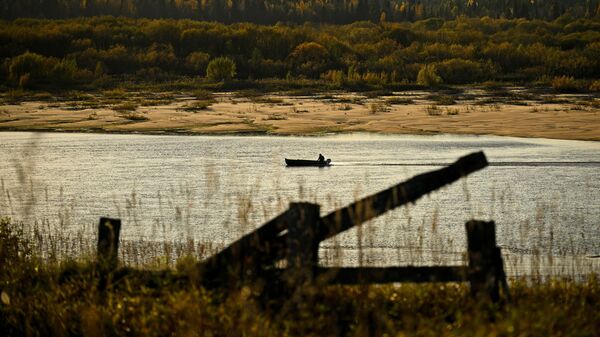 Рыбак плывет на лодке по реке Пинега в Архангельской области