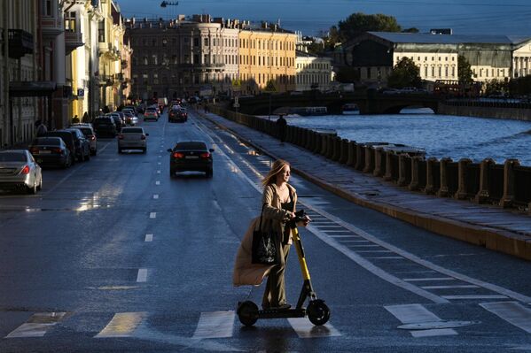 Девушка на самокате на набережной реки Мойка в Санкт-Петербурге