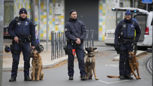 Кинологи бельгийской полиции стоят за оцепленным районом недалеко от места в Брюсселе, где был застрелен подозреваемый в нападении на болельщиков