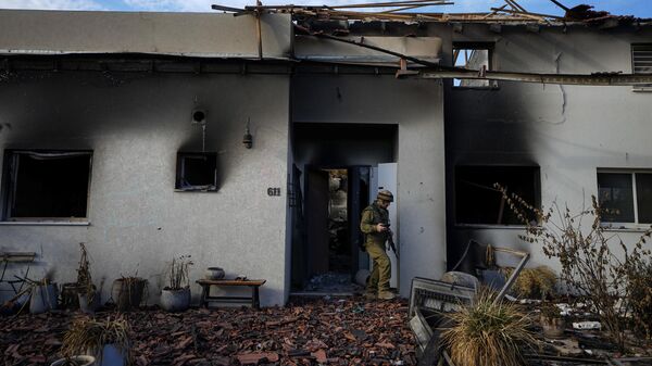 Израильский солдат осматривает дом, поврежденный боевиками Хамаса