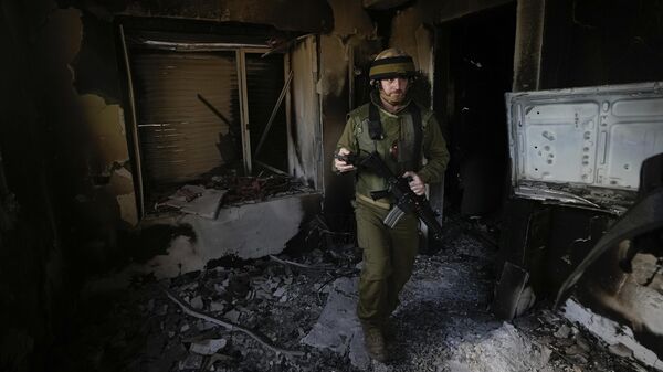 Израильский солдат осматривает дом, поврежденный боевиками Хамаса в кибуце Беэри в Израиле