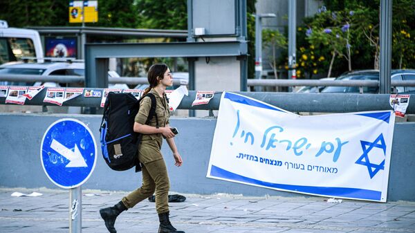 Военнослужащая армии обороны Израиля на фоне патриотической агитации в Тель-Авиве