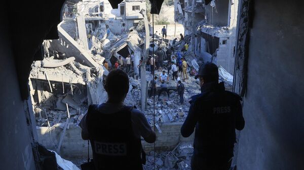 Палестинцы на месте разрушенных после израильской бомбардировки домов в Рафахе на юге сектора Газа