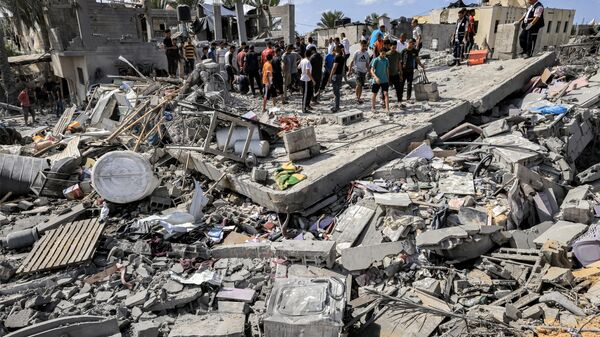 Люди на месте разрушенного после израильской бомбардировки здания в Хан-Юнисе на юге сектора Газа