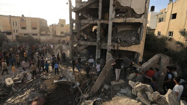 Палестинцы на месте разрушенного от израильского удара здания в Хан-Юнисе на юге сектора Газа