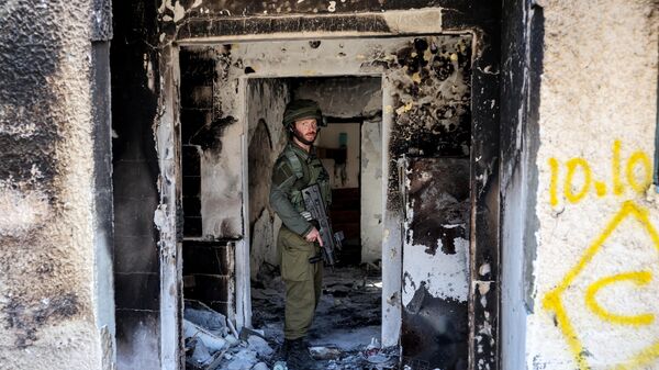 Солдат израильской армии в сгоревшем здании во время патрулирования в кибуце Кфар-Аза на юге Израиля недалеко от сектора Газа