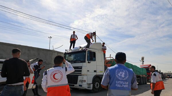Сотрудники гуманитарных организаций у грузовиков с гумпомощью для сектора Газа