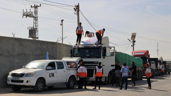 Сотрудники гуманитарных организаций вокруг грузовиков с гуманитарной помощью, въехавших в сектор Газа из Египта через КПП Рафах