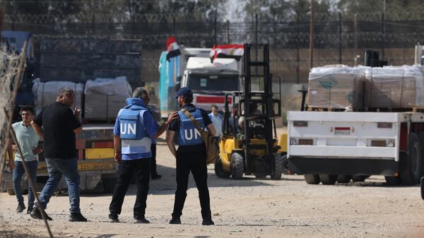 Сотрудники ООН около грузовиков с гуманитарной помощью, которые въехали в сектор Газа из Египта через пограничный переход Рафах