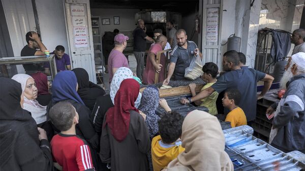 Люди стоят в очереди за хлебом возле пекарни в Рафахе на юге сектора Газа