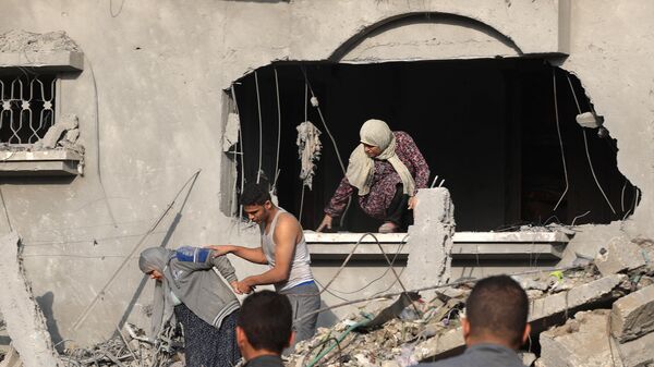 Палестинец помогает эвакуировать женщину из поврежденного здания после ночных израильских ударов по Рафаху на юге сектора Газа
