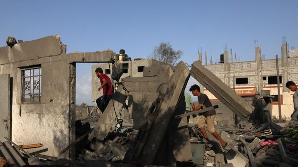 Палестинцы на месте разрушенного после ночного израильского авиаудара здания в Рафахе на юге сектора Газа