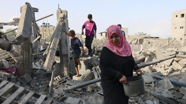 Палестинцы на руинах домов после ночных израильских ударов по Рафаху