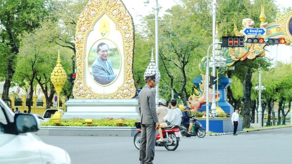 Офицер тайской полиции стоит на перекрестке перед портретом короля Пхумипона Адульядета в центре Бангкока 