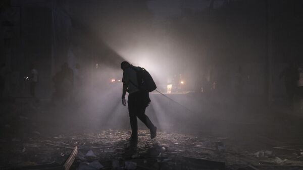 Мужчина идет по заваленной обломками улице после авиаударов Израиля по городу Газа
