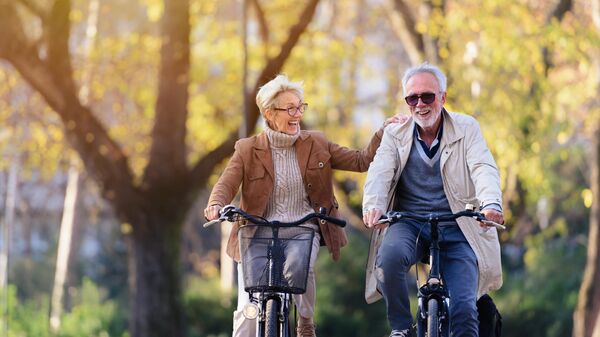 Пожилая пара катается на велосипедах в парке