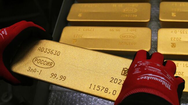 Сотрудник помещает на тележку готовый маркированный слиток золота высшей пробы 99,99 процента чистоты