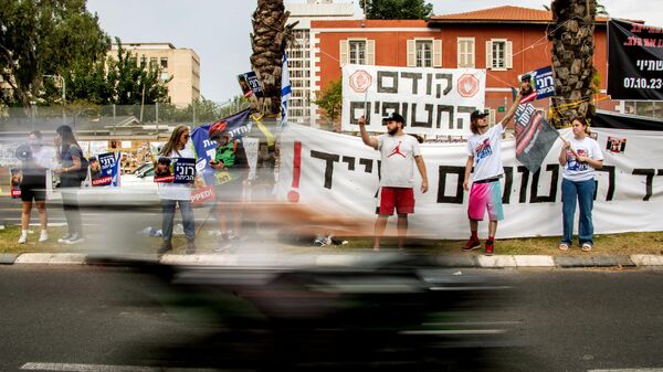 Участники акции за прекращение огня и освобождение заложников, уведенных палестинской группировкой ХАМАС в Газу, на одной из улиц в центре Тель-Авива