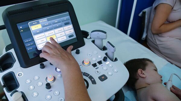 Специалист проводит ультразвуковое исследование ребёнку в клинической поликлинике 