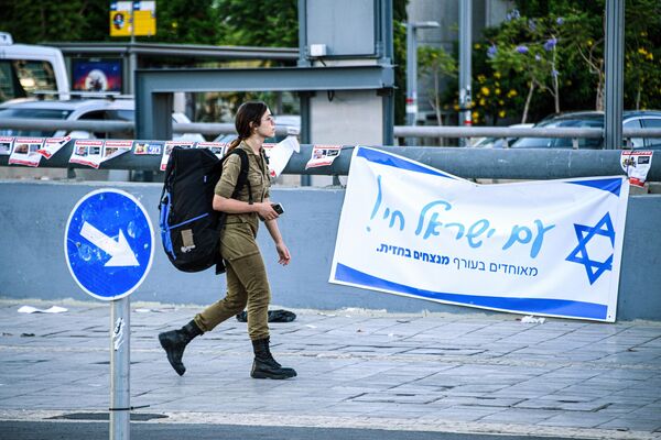 Военнослужащая армии обороны Израиля (ЦАХАЛ) на фоне патриотической агитации в Тель-Авиве
