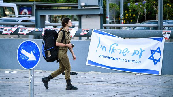 Военнослужащая Армии обороны Израиля (ЦАХАЛ) на фоне патриотической агитации в Тель-Авиве
