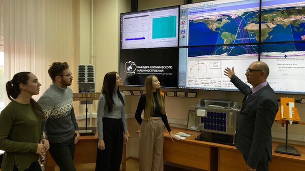Профессор Андрей Седельников с группой аспирантов и магистрантов обсуждают детали движения малых космических аппаратов в Центре приема и обработки космической информации