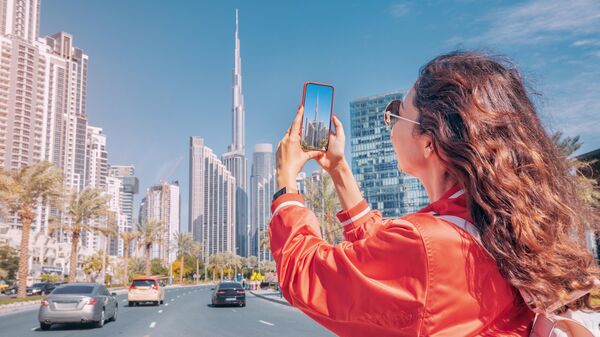 Девушка фотографирует небоскреб Бурдж-Халифа в Дубае