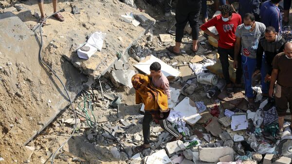 Палестинец с телом ребенка, извлеченным из-под завалов здания, разрушенного израильской бомбардировкой
