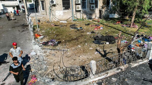 Люди на территории  больницы Ахли Араб в центре Газы, разрушенной ракетным ударом