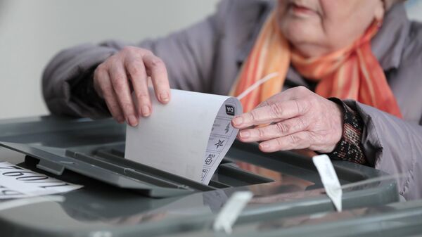 Женщина опускает бюллетень в урну на избирательном участке в Кишиневе