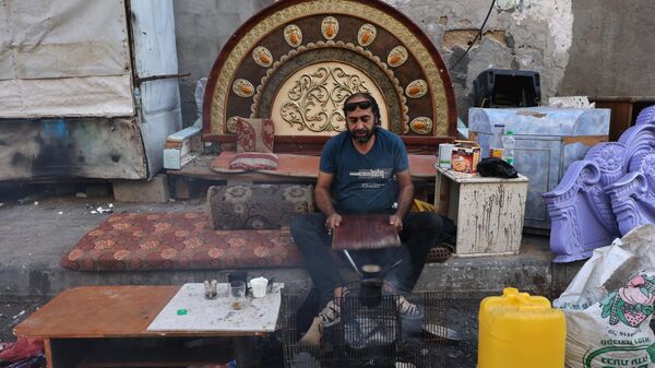Мужчина рядом со своими вещами, извлеченными из-под завалов в Рафахе на юге сектора Газа