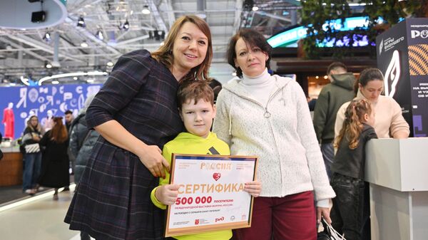 Наталья Виртуозова, генеральный директор выставки достижений Россия, и 500-тысячный посетитель мальчик Матвей Гузев со своей мамой Татьяной Гузевой