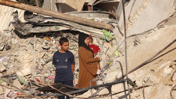 Пострадавшие от израильских авиаударов около руин своего дома в городе Рафах на юге сектора Газа