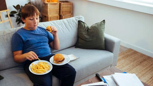 Мальчик с лишним весом ест бургер