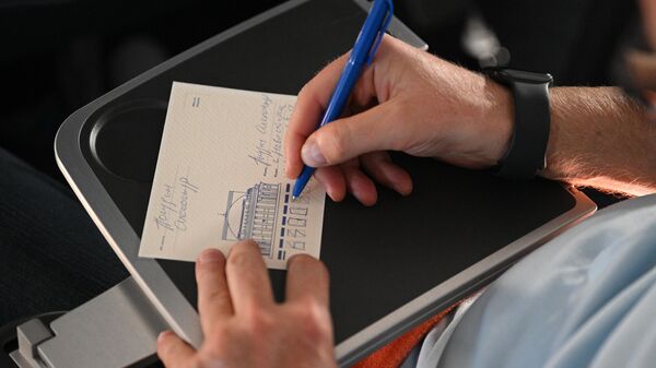 Пассажир самолета Airbus А321 авиакомпании Аэрофлот, выполняющего 11 ноября ретрорейс SU1460/SU1461 по маршруту Москва - Новосибирск - Москва, подписывает сувенирную открытку, чтобы отправить ее во время рейса