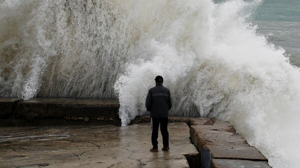 Мужчина на берегу Черного моря в Сочи в штормовую погоду