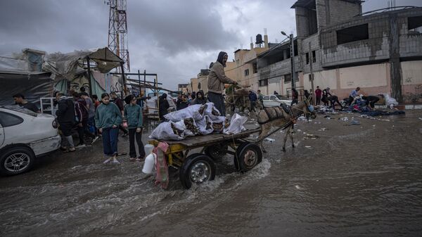 Палестинцы на затопленной улице рядом с лагерем для перемещенных лиц в городе Хан-Юнис