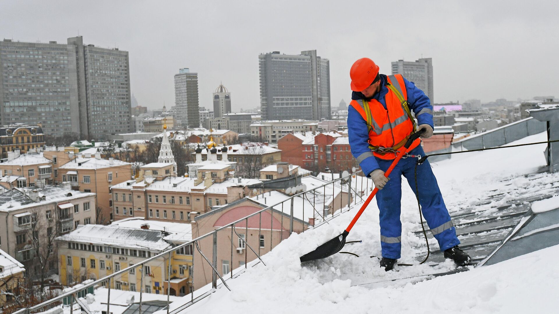 Сотрудник коммунальных служб отчищает крышу одного из домов в Москве - РИА Новости, 1920, 25.11.2023