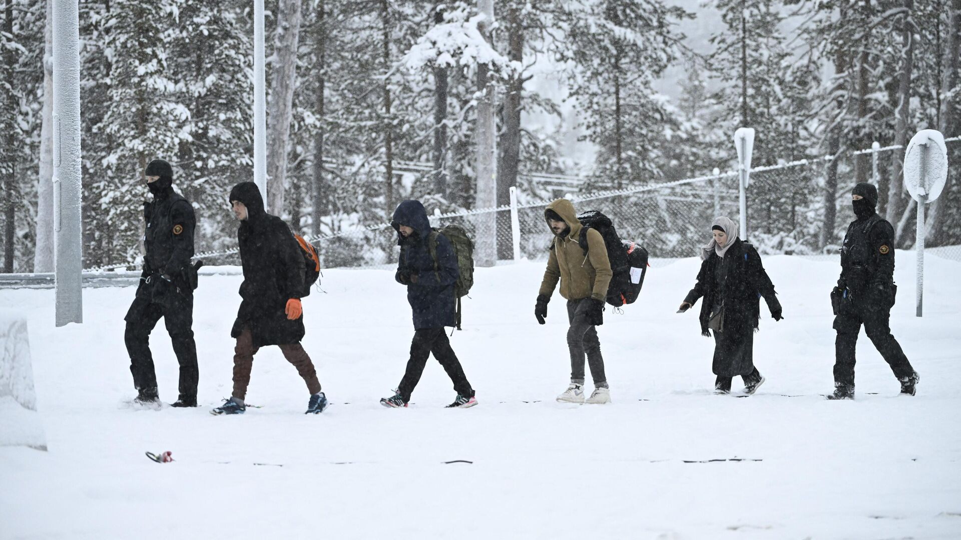 Офицеры финской пограничной службы сопровождают мигрантов на КПП Райа-Йоосеппи в северной Финляндии. 25 ноября 2023 - РИА Новости, 1920, 25.11.2023