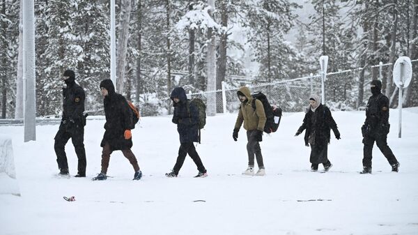 Офицеры финской пограничной службы сопровождают мигрантов на КПП Райа-Йоосеппи в северной Финляндии. 25 ноября 2023