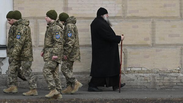 Украинские военнослужащие проходят мимо монаха в Киево-Печерской Лавре