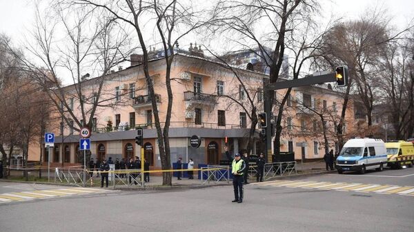 Сотрудник полиции регулирует движение у хостела в Алма-Ате, где произошел пожар