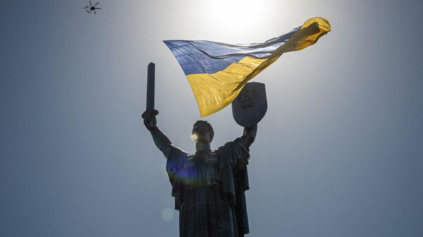 Дрон с украинским национальным флагом пролетает над памятником Родина-мать в Киеве