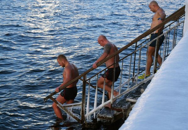 Мужчины купаются в морозный день на обледенелой набережной Спортивной гавани во Владивостоке