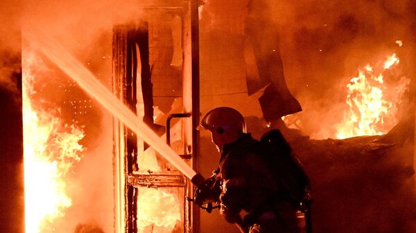 Сотрудник пожарной службы тушит пожар на вещевом рынке Темерник в Ростове-на-Дону